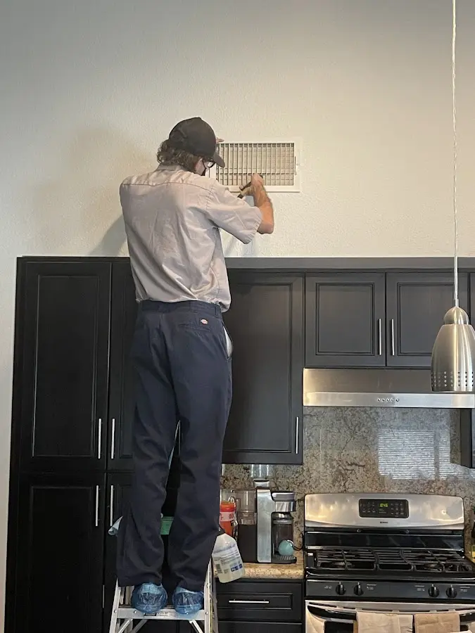 Technician inspecting an air vent during HVAC service in Busti